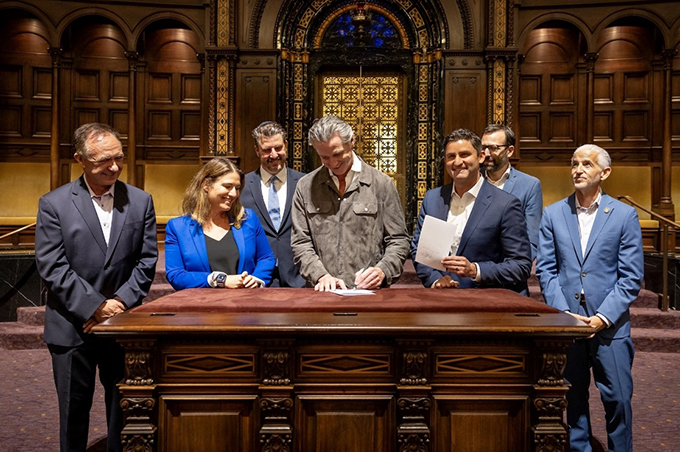 Governor Gavin Newsom signing a bill alongside 6 members of the California Legislative Jewish Caucus.